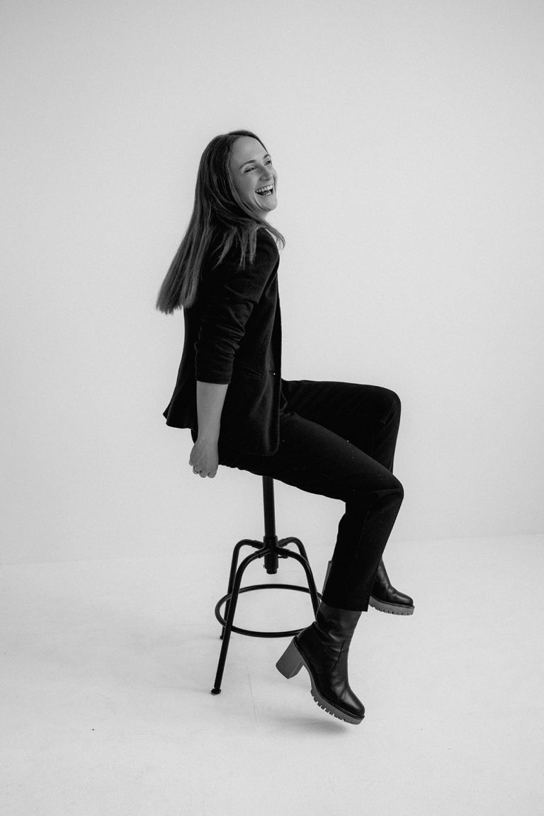 Vera Özkaya sitzt auf einem Hocker und lacht