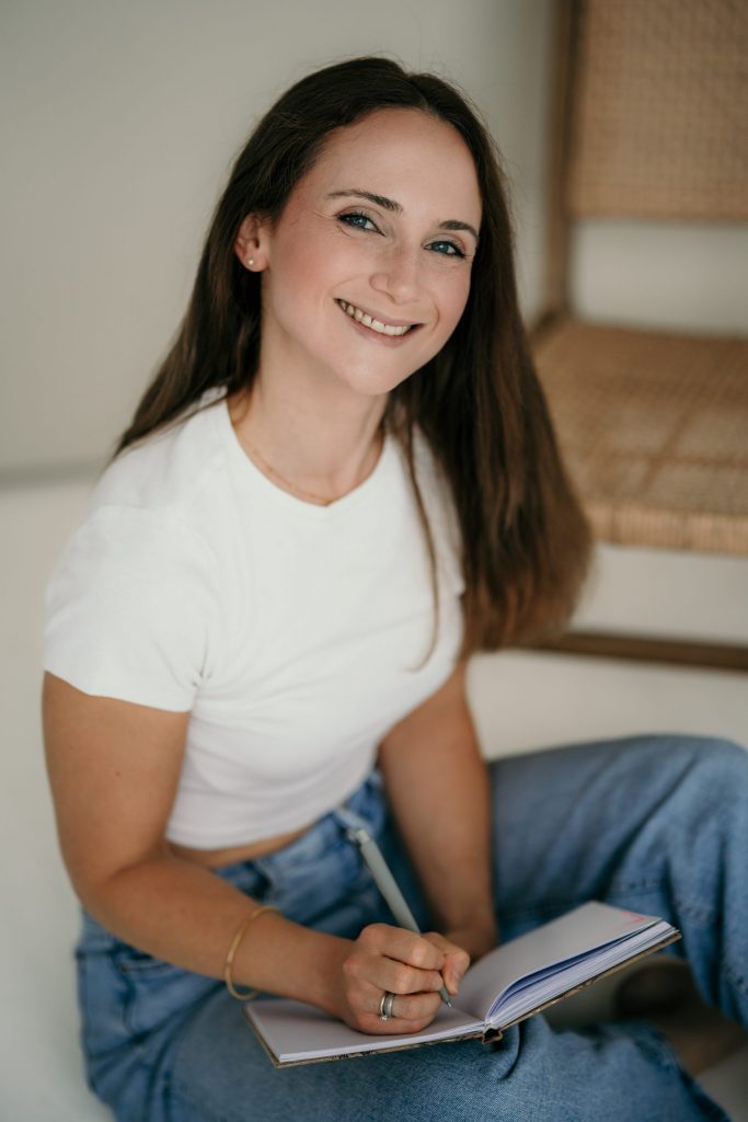 Vera Özkaya sitzt mit einem Notizbuch auf dem Boden